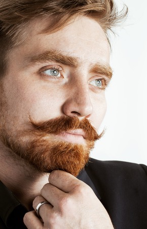 young red hair man with beard and mustache in black suit on white background close upの写真素材