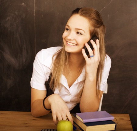 young pretty girl student in classroom at blackboard doing homeworkの写真素材