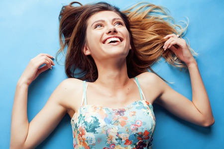 young pretty woman fooling around on blue background close up smilingの写真素材
