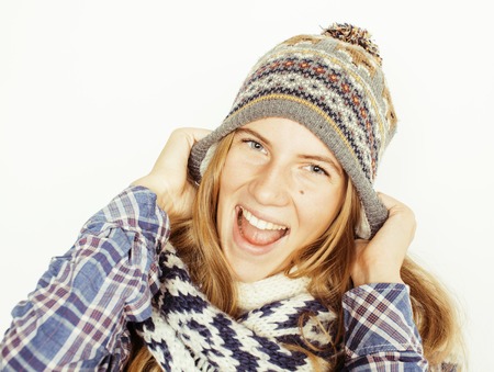 young pretty blond teenage girl in winter hat and scarf on white background smiling close upの写真素材