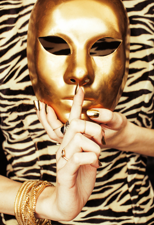 woman hands holding golden carnival mask, rich luxury manicure and jewelry close up on zebra printの写真素材