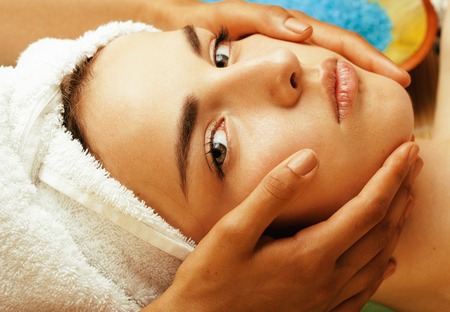 attractive lady getting spa treatment in salon, close up asian tan hands on faceの写真素材