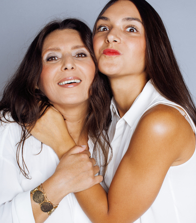 cute pretty teen daughter with mature mother hugging, fashion style brunette makeup close upの写真素材