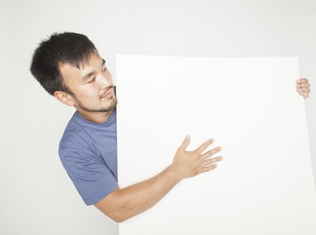 pretty cool asian man holding empty white plate smiling, making advertの写真素材