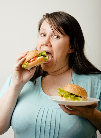 fat white woman having choice between hamburger and salad emotionalの写真素材