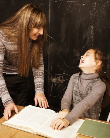 teacher with pupil in classroom at blackboard writting, girl at school preswchoolerの写真素材
