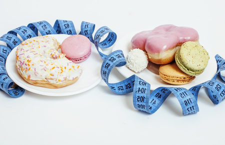 new diet concept, question sign in shape of measurment tape between red apple and donut plus candy isolated on whiteの写真素材