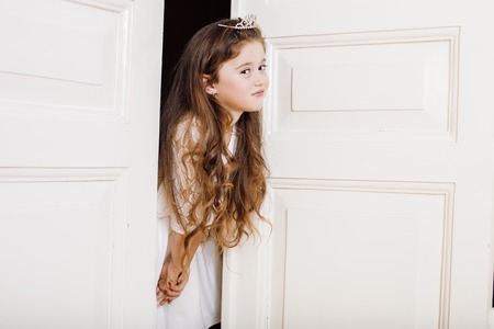 little cute girl at home, opening door well-dressed in white dress, adorable milk fairy. front teeth goneの写真素材