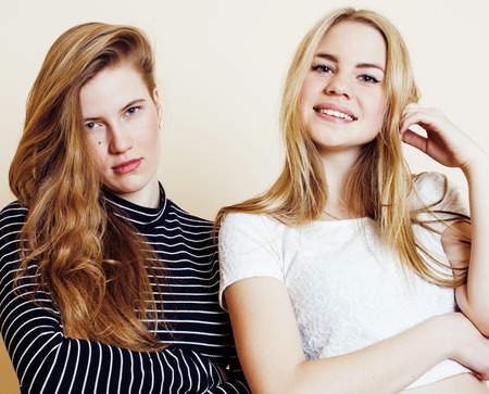 lifestyle and people concept: Fashion portrait of two stylish sexy girls best friends, over white background. Happy time for fun. One with hard feelingsの写真素材