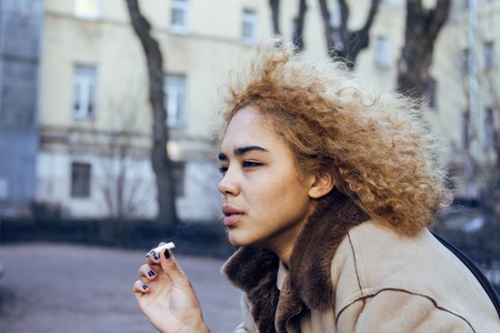 young pretty girl teenage outside smoking cigarette close up, looking like real junky, social issues conceptの写真素材