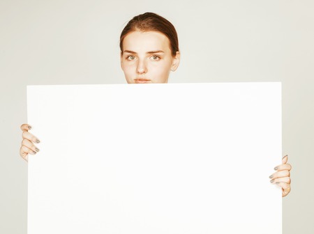 young pretty brunette girl with placard shit copyspace on white background wearing business costume studentの写真素材