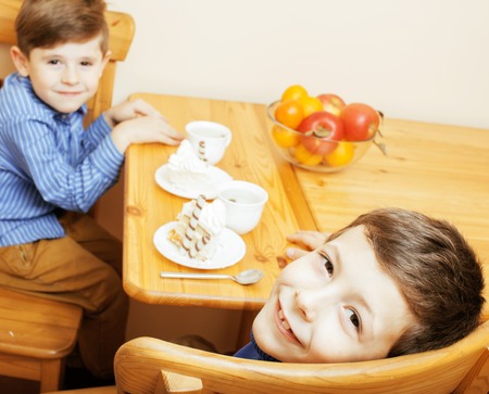 little cute boys eating dessert on wooden kitchen. home interior. smiling adorable, lifestyle people conceptの写真素材