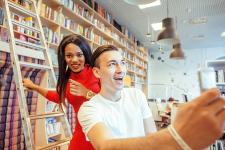 couple students in univercity library, looking book, preparing to exam, having fun, making selfie, lifestyle people conceptの写真素材