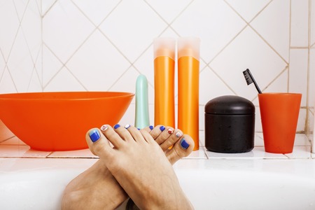 woman legs in bathroom with lot of stylish stuff for care, pedicure creative design blue, hygiene conceptの写真素材