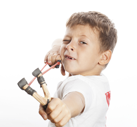 little cute angry real boy with slingshot isolated on white background close upの写真素材