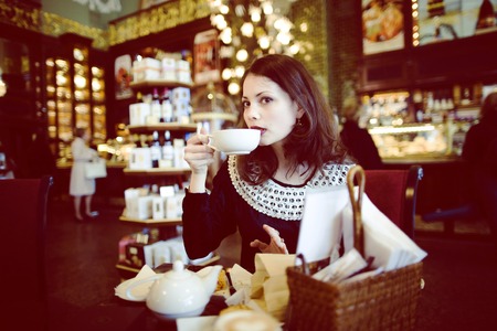 young elegant brunette rich woman in cafe drinking coffee, luxury vintage interiorの写真素材