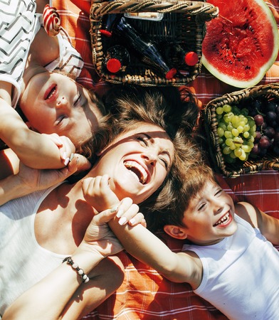 cute happy family on picnic laying on green grass mother and kids, warm summer vacations close up, brother and sister, happy children lifestyle conceptの写真素材