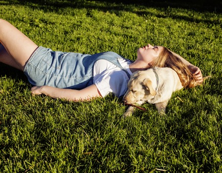 young attractive blond woman playing with her dog in green park at summer, lifestyle people concept,...