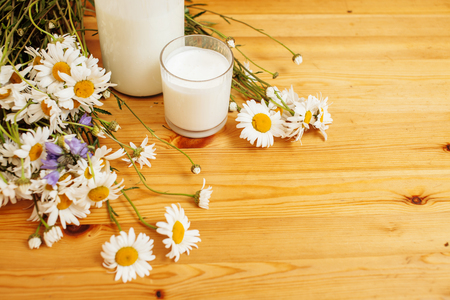 Simply stylish wooden kitchen with bottle of milk and glass on table, summer flowers camomile, healthy foog moring concept nooneの写真素材