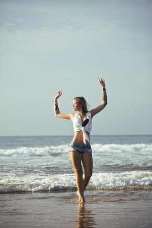 young pretty blond woman at seacoast walking relaxing, fashion lady at sunset, cool vacationsの写真素材