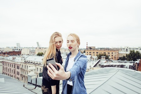 two cool blond real girls friends making selfie on roof top, lifestyle people concept, modern teensの写真素材