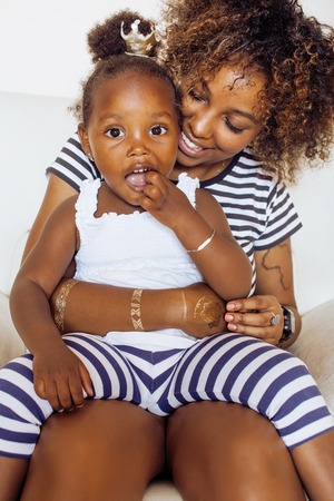 adorable sweet young afro-american mother with cute little daughter, hanging at home, having fun playing smiling, lifestyle people conceptの写真素材