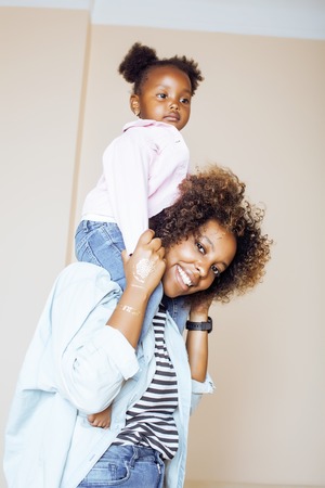 adorable sweet young afro-american mother with cute little daughter, hanging at home, having fun playing smiling, lifestyle people conceptの写真素材