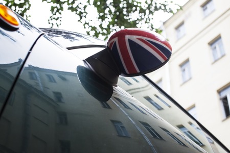 vintage car detail, concept of British Patriotism shown as flag on mirror, trees in reflection windshield, body partの写真素材