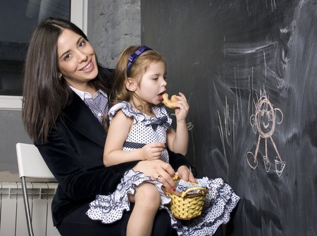 teacher with pupil in classroom at blackboard writting, mother and daughter first time to school, lifestyle people conceptの写真素材