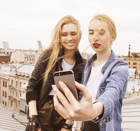 two cool blond real girls friends making selfie on roof top, lifestyle people concept close upの写真素材