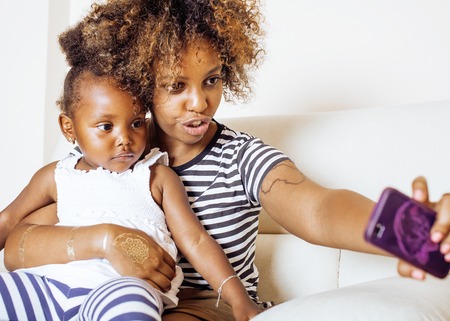adorable sweet young afro-american mother with cute little daughter, hanging at home, having fun playing smiling, lifestyle people conceptの写真素材