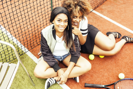 young pretty girlfriends hanging on tennis court, fashion stylish dressed swag, best friends happy smiling together close upの写真素材