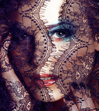 portrait of beauty young woman through lace, bright make up smiling, manicure on hands close upの写真素材