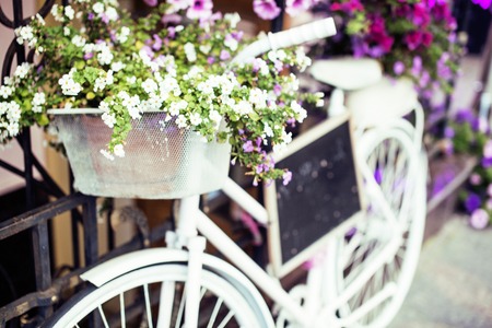 flower in basket of vintage bicycle on vintage wooden house wall, summer street cafe close upの写真素材