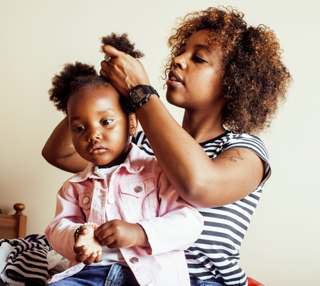modern young happy african-american family: mother combing daughters hair at home, lifestyle people concept close upの写真素材