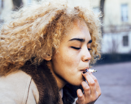 young pretty girl teenage outside smoking cigarette, looking like real junky, social issues concept close upの写真素材