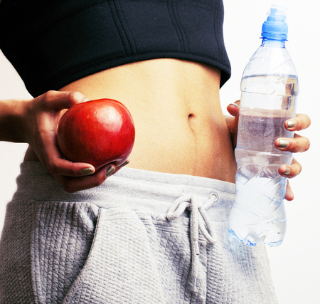 woman measuring waist with red apple and water, african tann isolated close upの写真素材