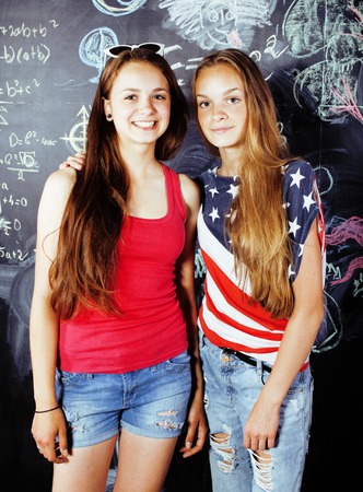 back to school after summer vacations, two teen real girls in classroom with blackboard painted together, lifestyle people conceptの写真素材