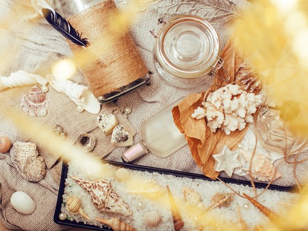 a lot of sea theme in mess like shells, candles, perfume, girl stuff on linen, pretty textured post card view vintage close upの写真素材