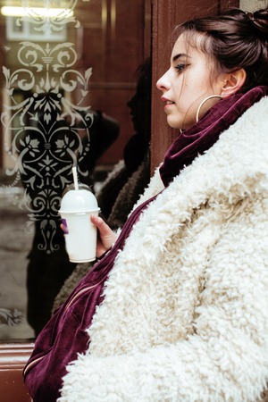 young pretty stylish teenage girl outside on city street fancy fashion dressed drinking milk shake,...