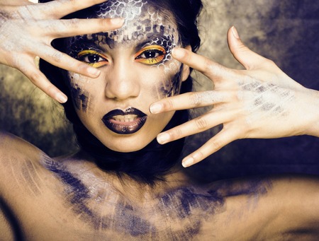 fashion portrait of pretty young woman with creative make up like a snake close upの写真素材