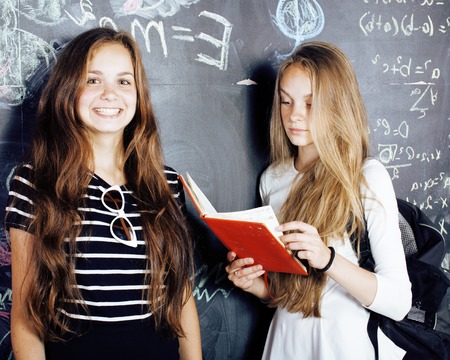 back to school after summer vacations, two teen real girls in classroom with blackboard painted together close upの写真素材