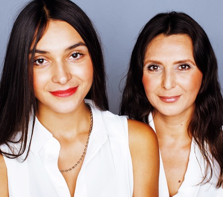 cute pretty teen daughter with mature mother hugging, fashion style brunette makeup close up, real happy familyの写真素材