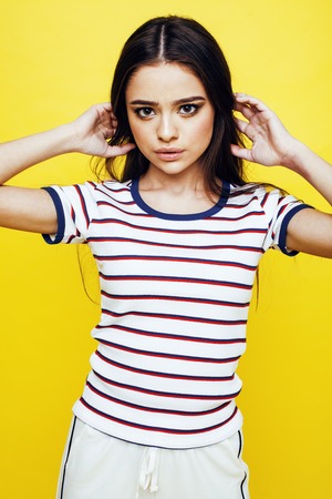 young pretty teenage woman emotional posing on yellow background, fashion lifestyle people conceptの写真素材