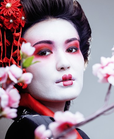 young pretty geisha in black kimono among sakura, asian ethnoの写真素材