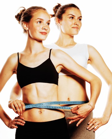 two sport girls measuring themselves isolated on whiteの写真素材