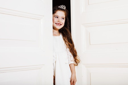 little cute girl at home, opening door well-dressed in white dreの写真素材