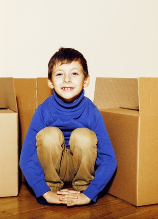 little cute boy in empty room, remoove to new house. home alone emong boxes close up kidの写真素材