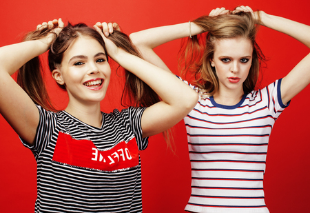 two best friends teenage girls together having fun, posing emotional on red background, besties...