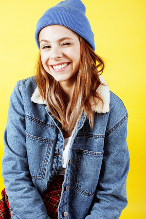 young pretty teenage hipster girl posing emotional happy smiling on yellow background, lifestyle people conceptの写真素材